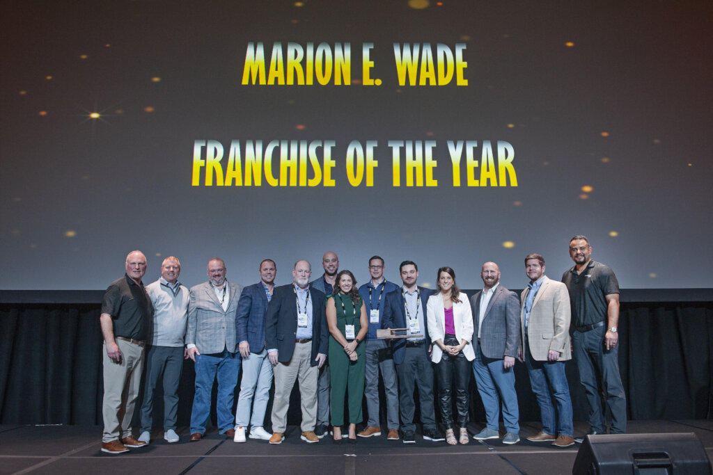 Caroline and Tyler Pattat with the ServiceMaster Restore leadership team accepting the 2022 Marion E. Wade Franchise of the Year award on stage